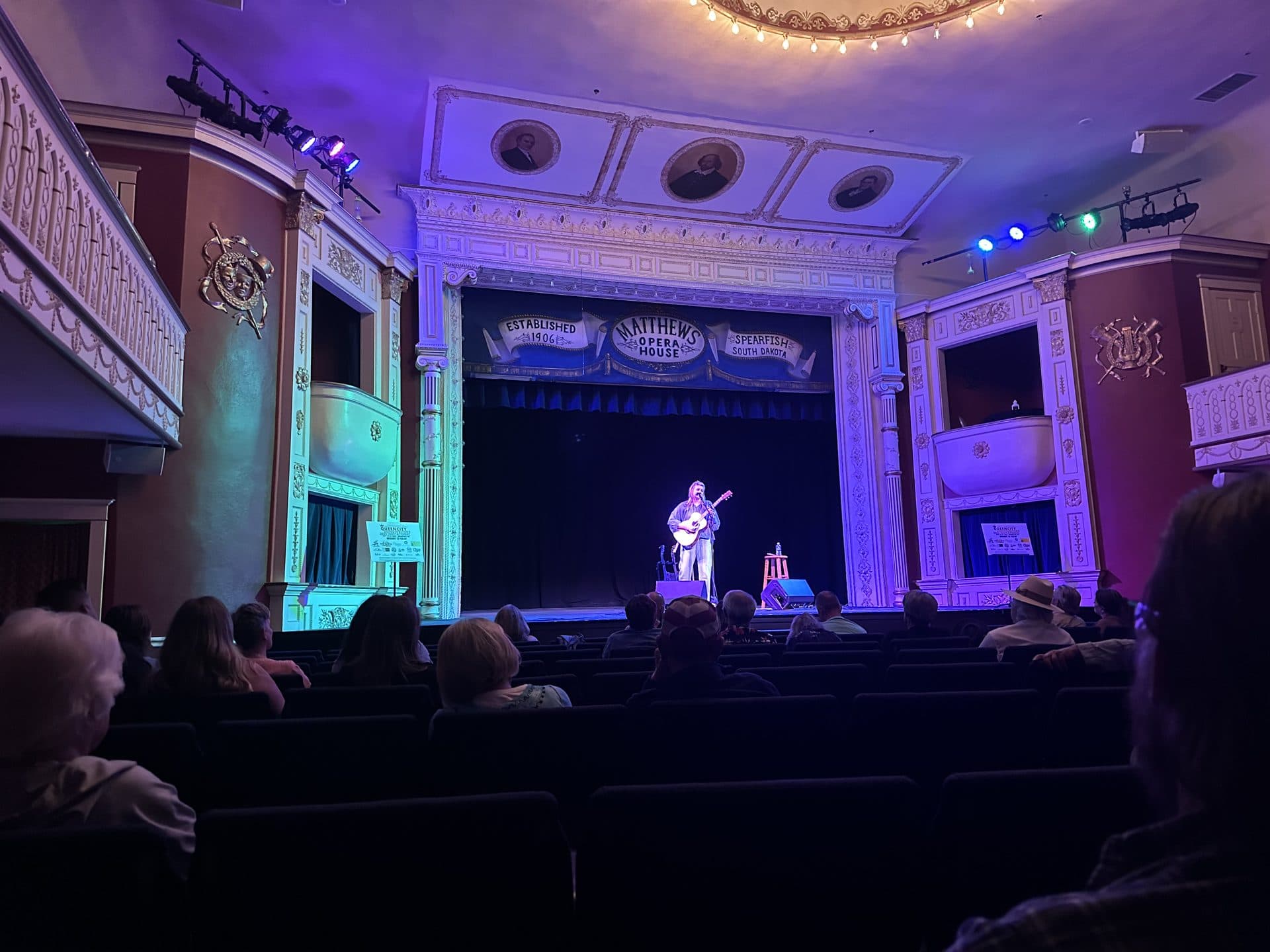 Songwriter performing on The Matthews Opera House stage during the Queen City Songwriters Invitational