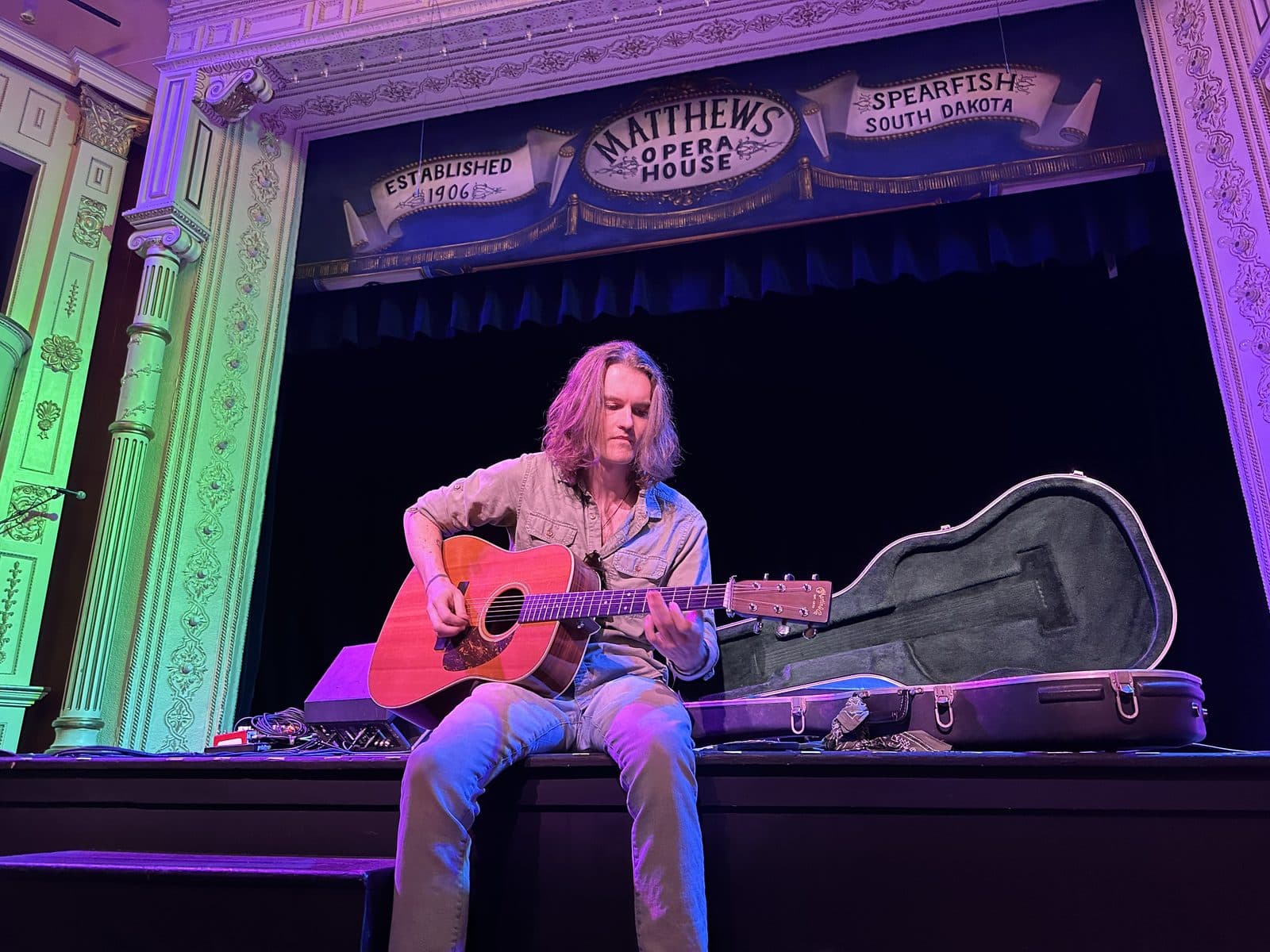 Songwriter performing on the edge of The Matthews Opera House stage